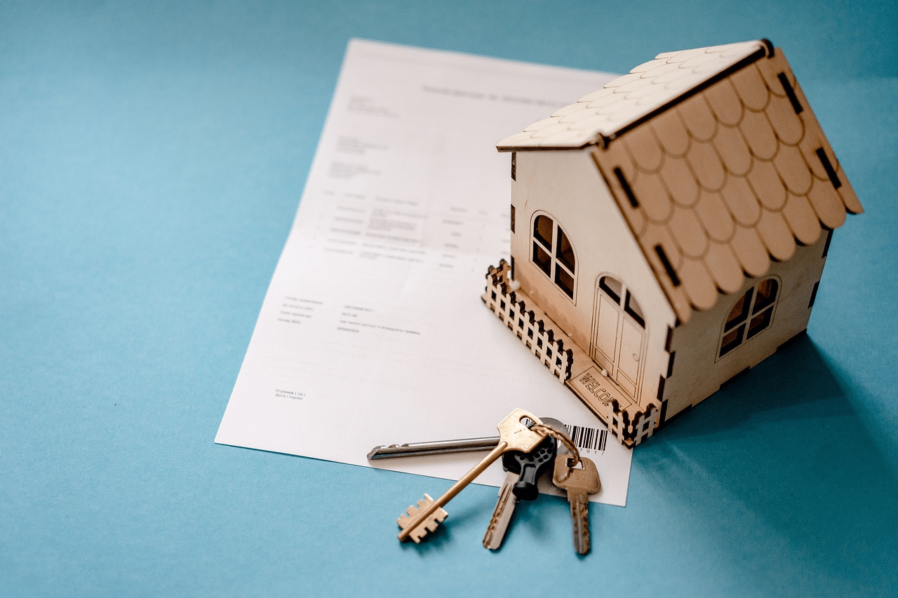 Ein Haus mit Schlüsseln auf einem Immobilienkaufvertrag einer Erbengemeinschaft
